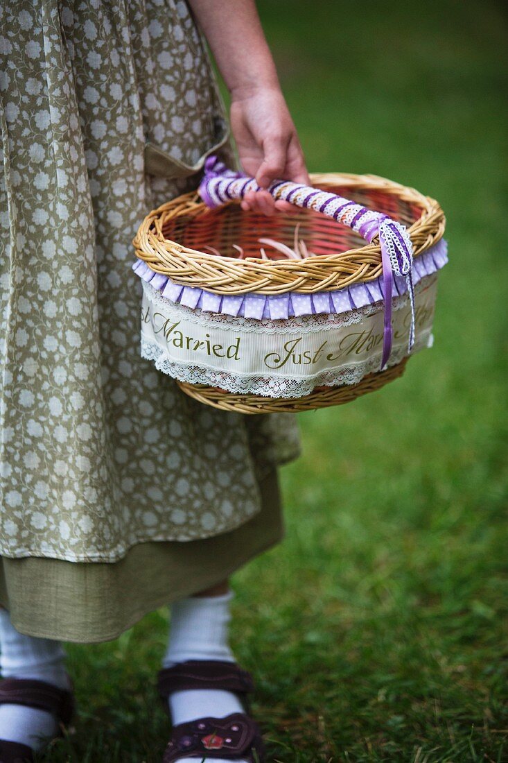 Girl in meadow holding basket of flowers