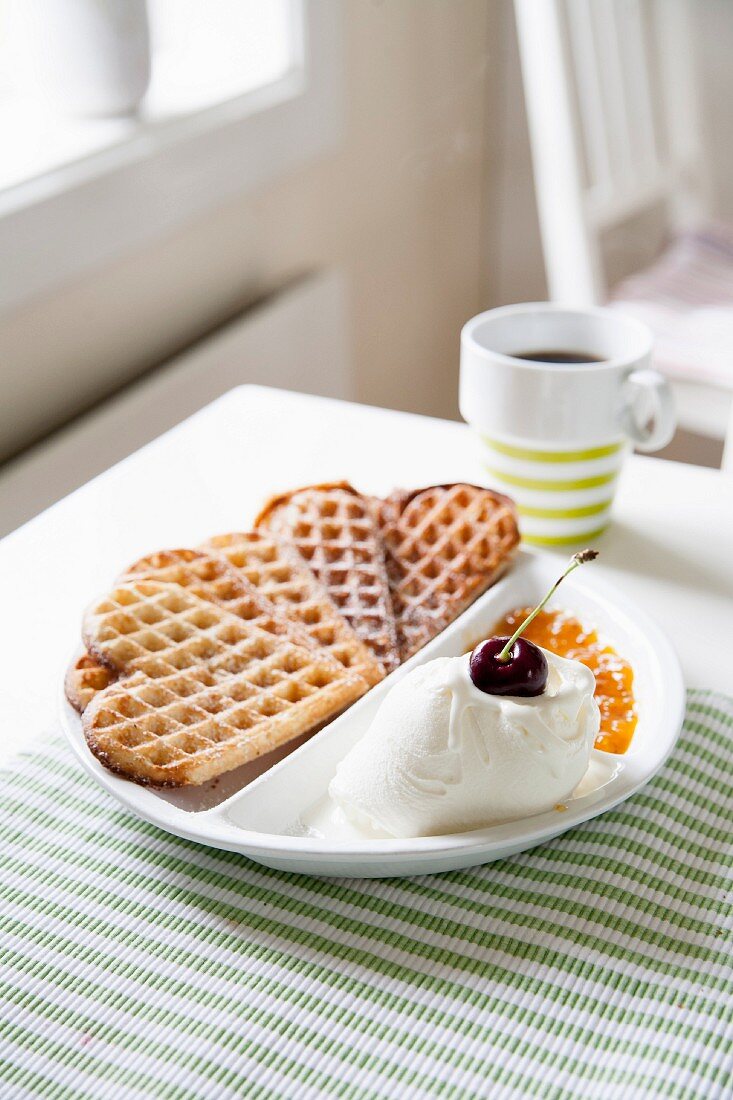 Heart-shaped waffles with vanilla ice cream and cloudberry jam