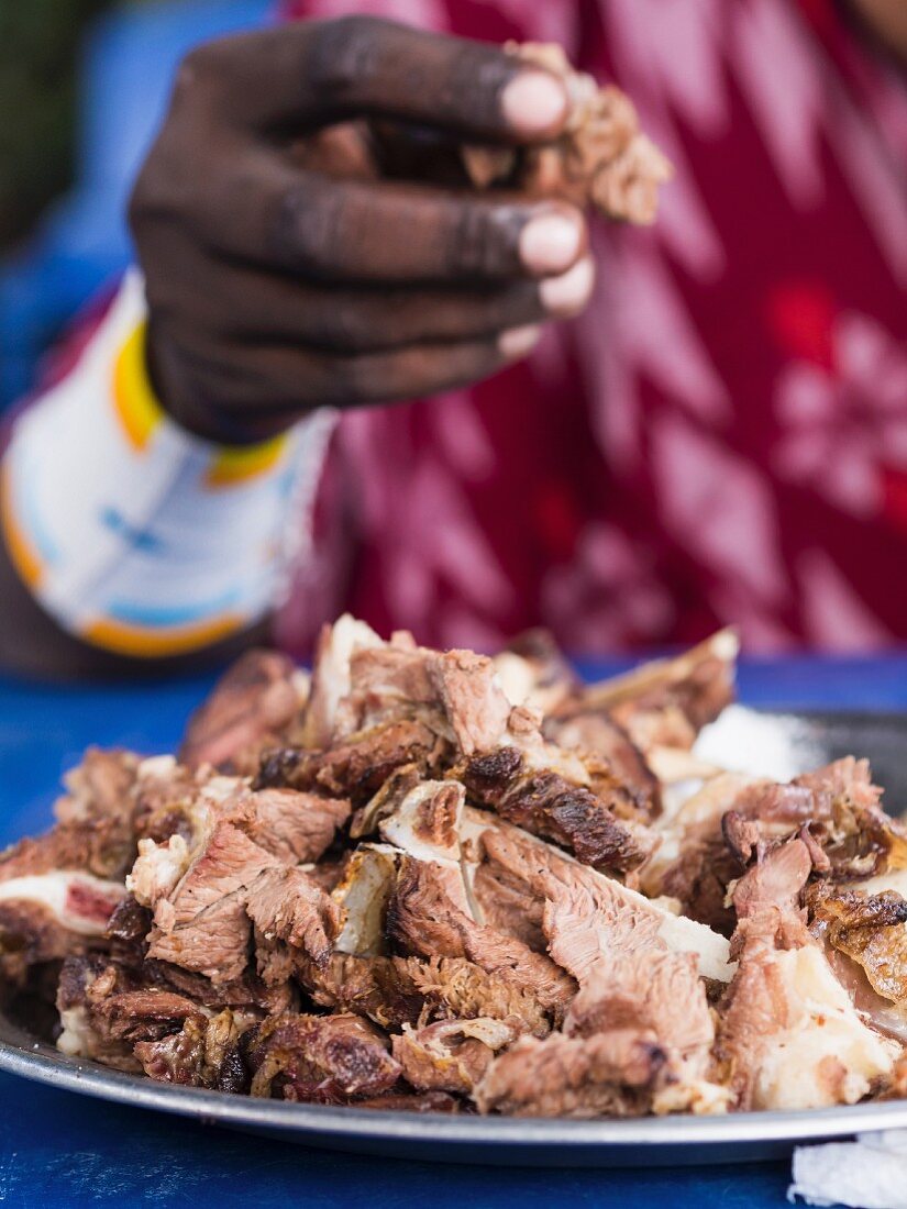 Massai-Krieger isst Nyama Choma (gegrilltes Fleisch, Tansania)