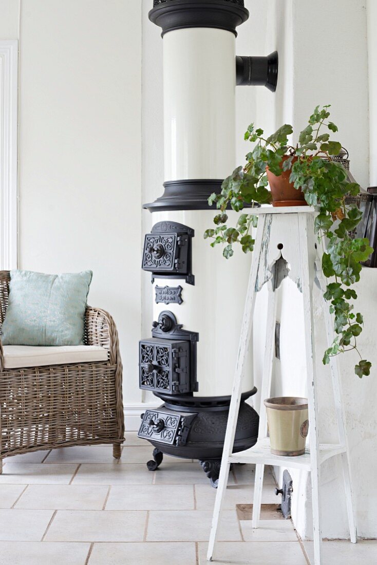 House plant on plant stand next to vintage stove and wicker chair