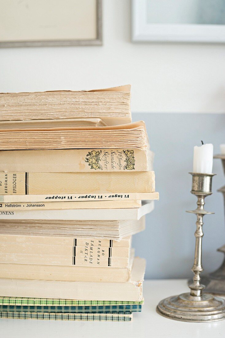 Stacked books and silver candlestick on shelf