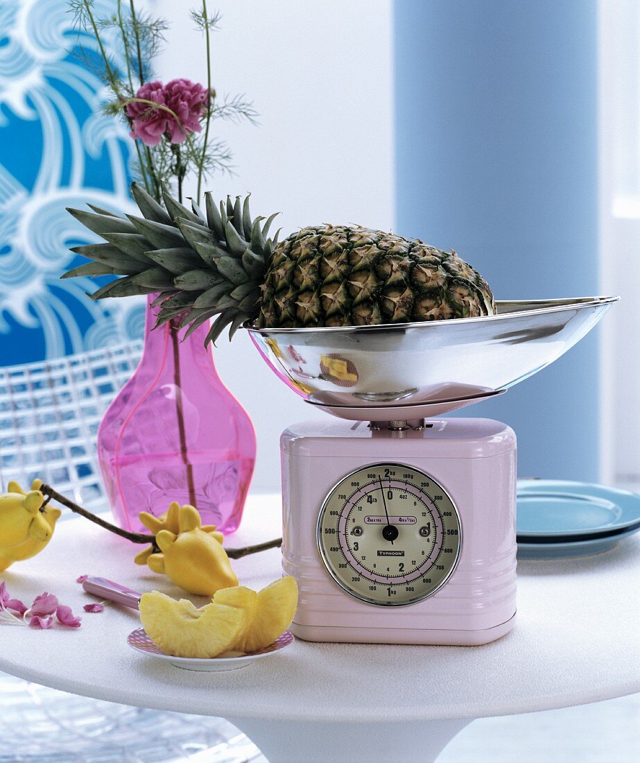 Pink retro kitchen scales and glass vase on round table