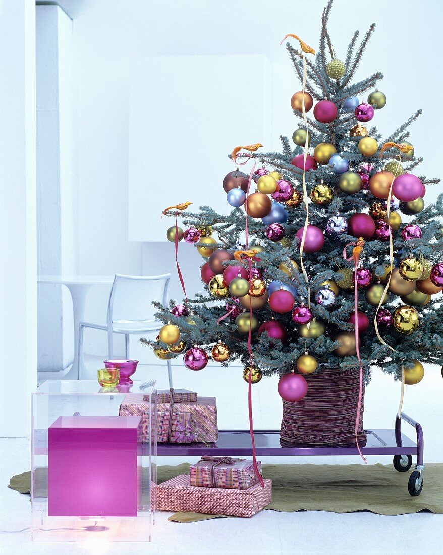 Geschmückter Christbaum dekoriert mit goldenen Paradiesvögeln und Kugeln in Pink, Gold und Silber