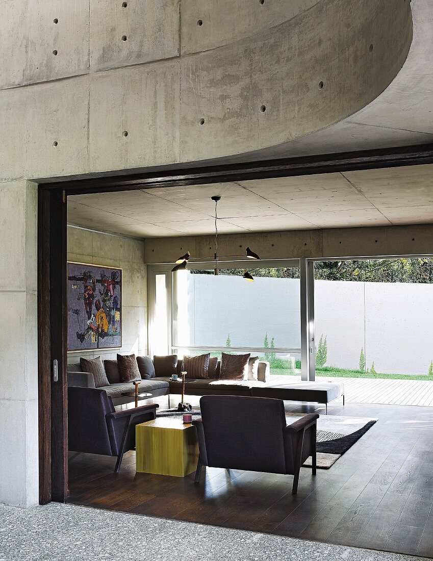 Blick ins moderne Wohnzimmer mit Wänden aus Beton und großer Fensterfront