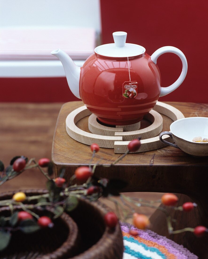 Red teapot on spiral birchwood trivet