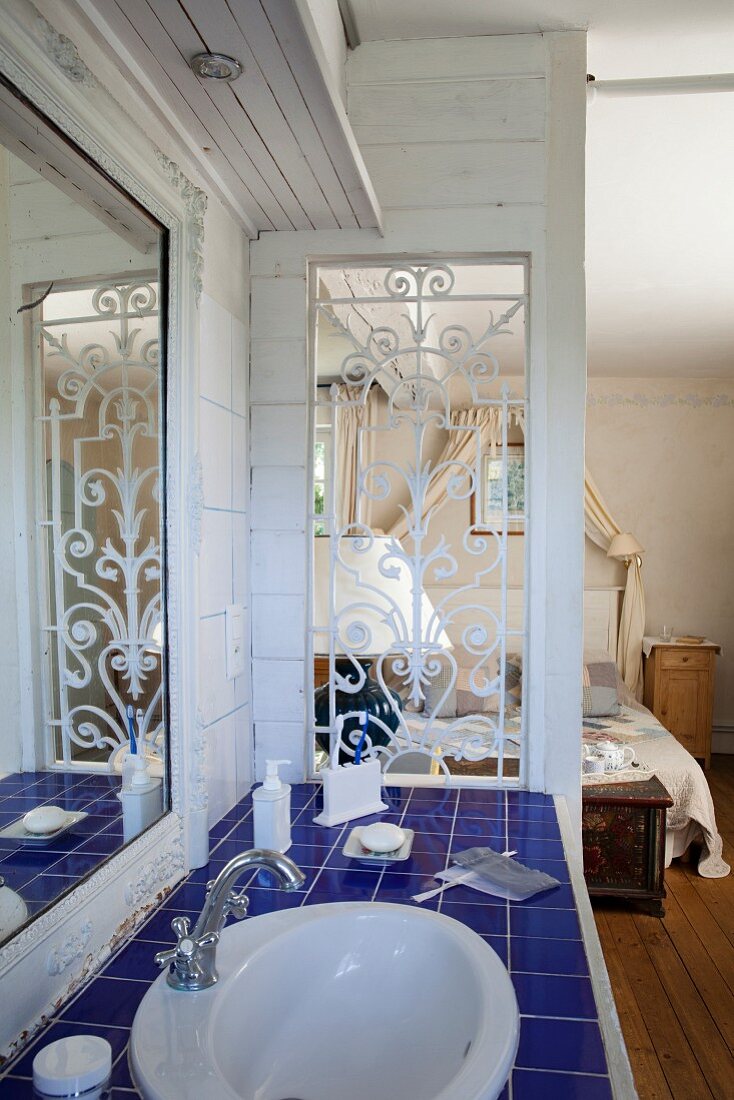 Washstand with blue-tiled counter next to partition between bathroom and bedroom