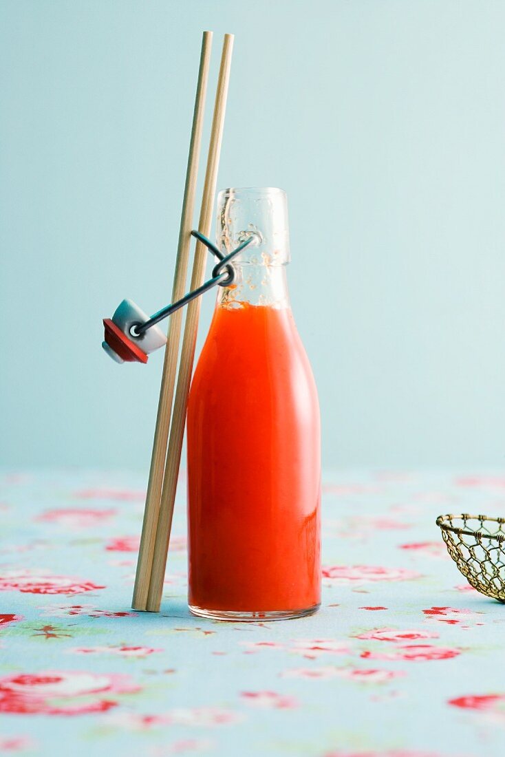 A bottle of chilli sauce with chopsticks