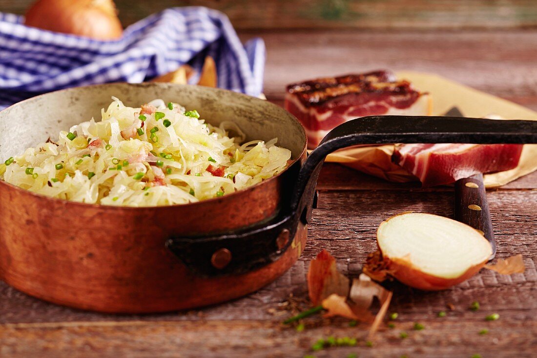 Bavarian coleslaw with onions and bacon in a copper pot