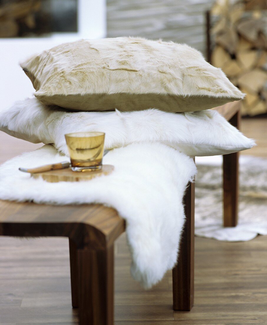 Fur cushion and sheepskin blanket on wooden bench