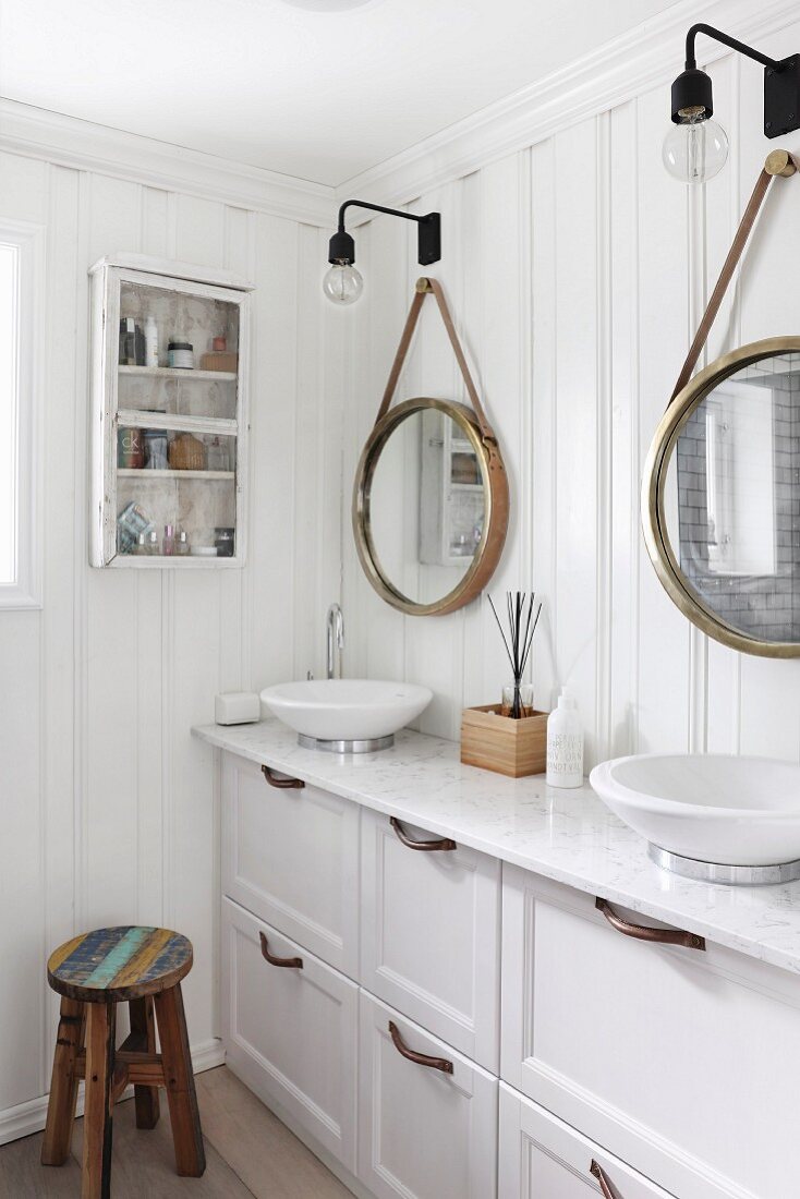 Waschtischzeile mit zwei Aufbaubecken in Weiß und Schubladenunterschrank, vor aufgehängten Spiegeln an weisser Holzwand