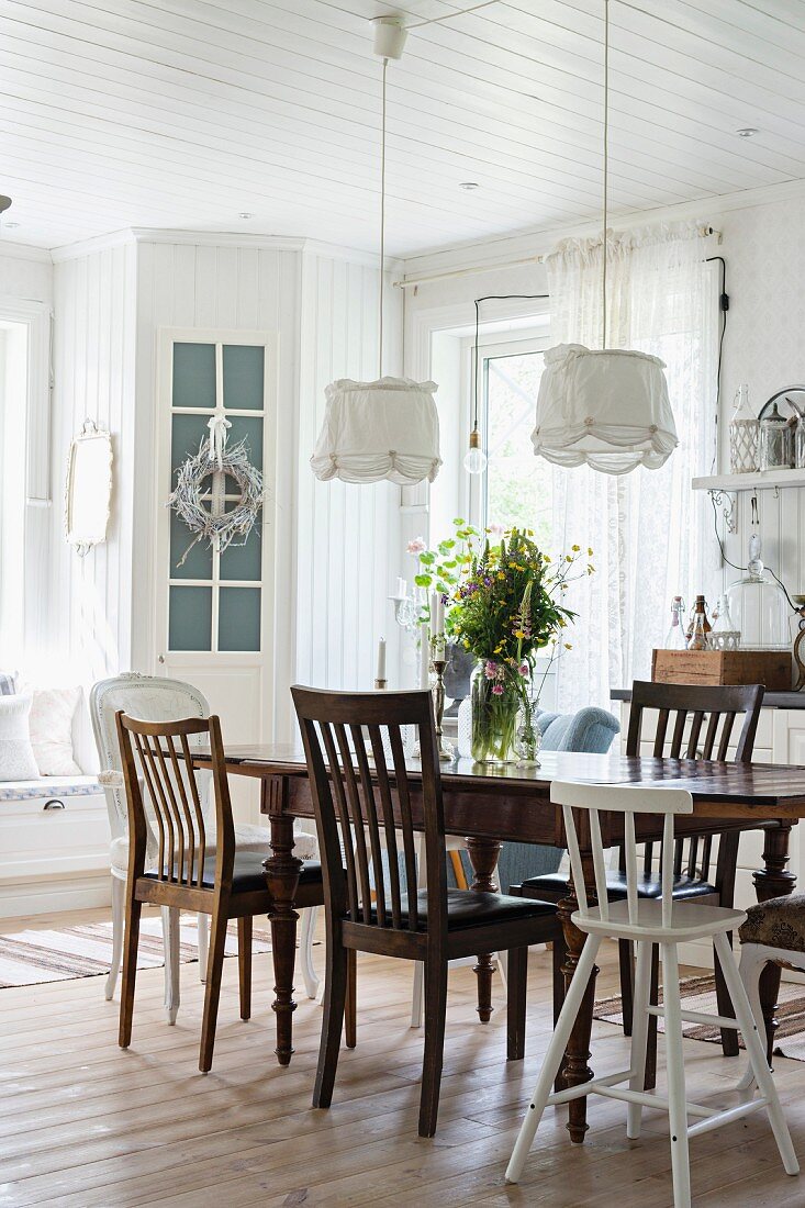 Various chairs around antique wooden table in kitchen