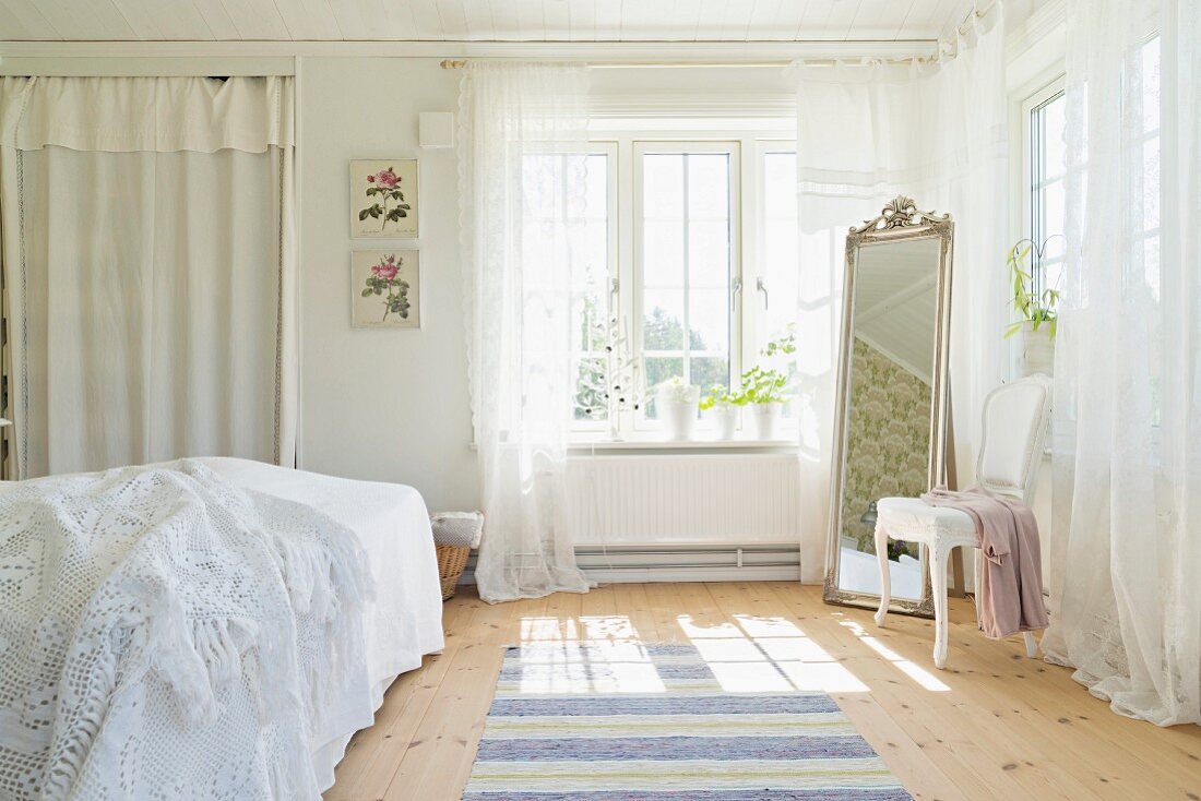 Romantisches Schlafzimmer mit weißen Vorhängen und einem Standspiegel