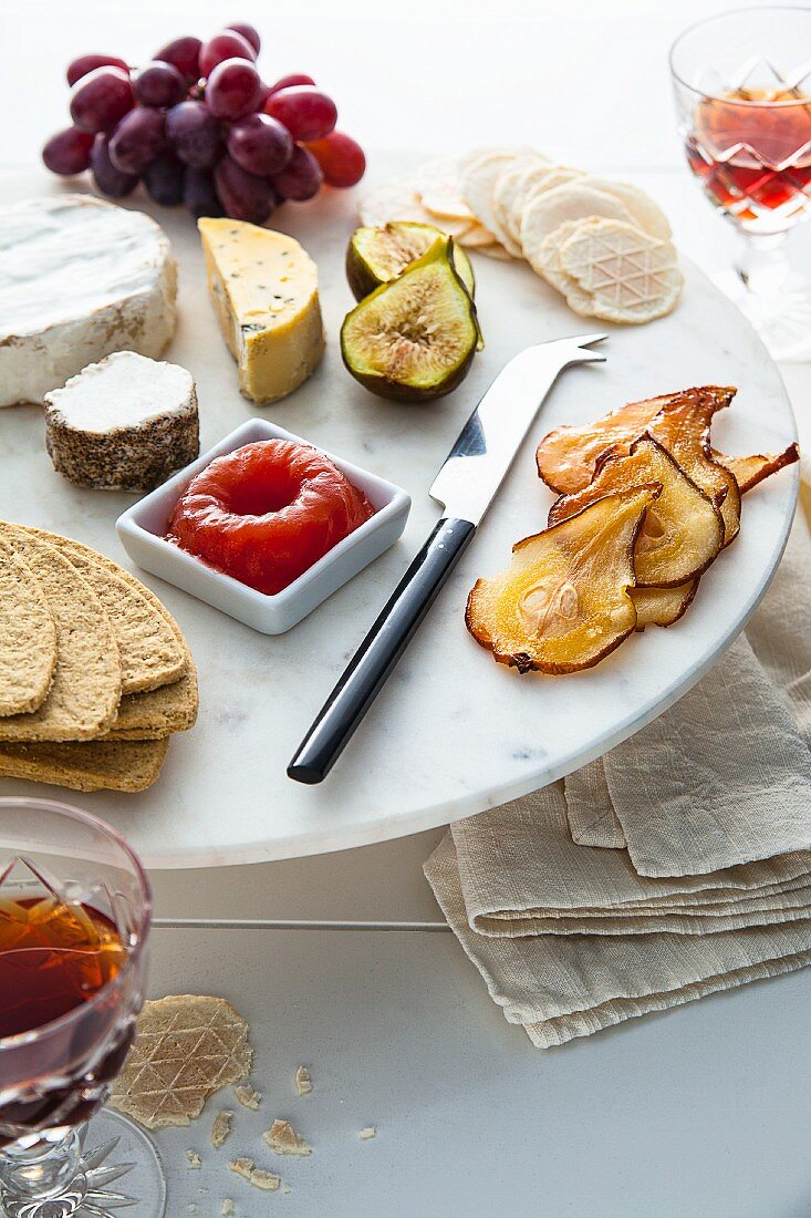 A cheese platter with quince jelly, grapes, figs and pears