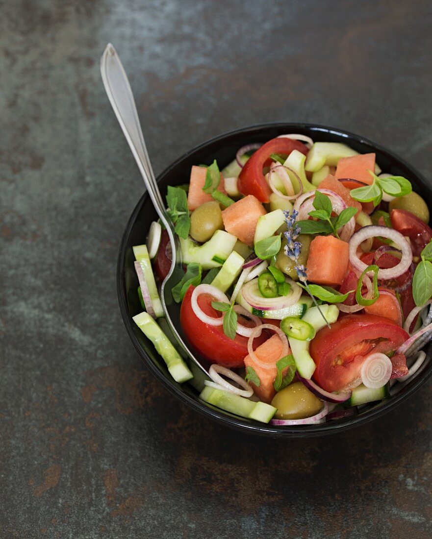 Fresh salad with tomatoes, cucumber, onions, olives, watermelon and herbs