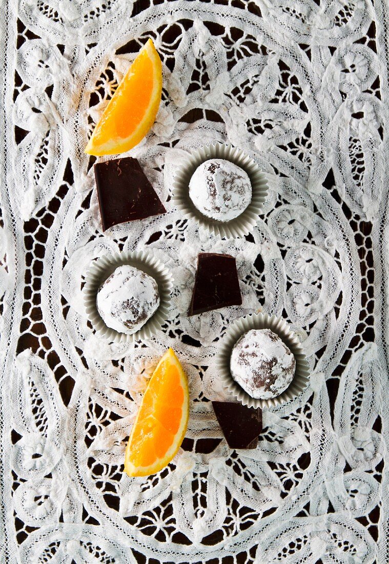 Vegan chocolate orange truffles on white lace cloth (seen from above)