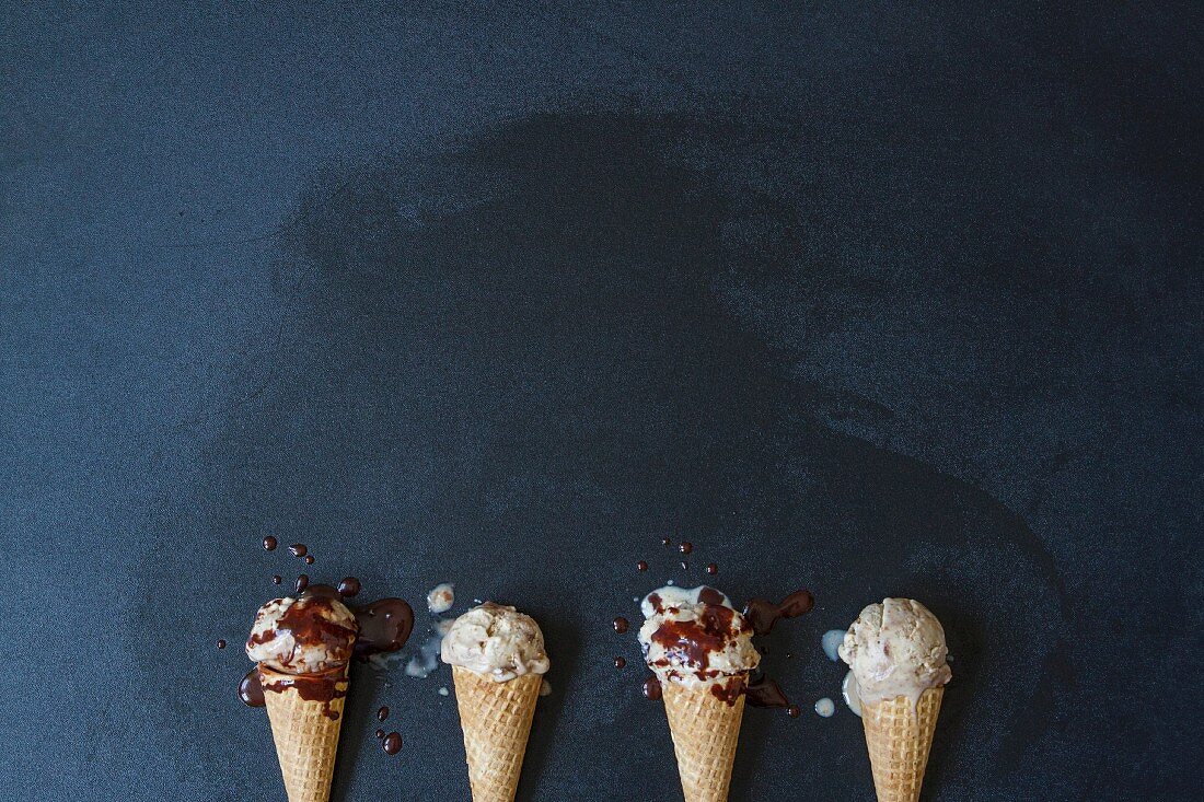 Four vegan ice cream cones with chocolate sauce