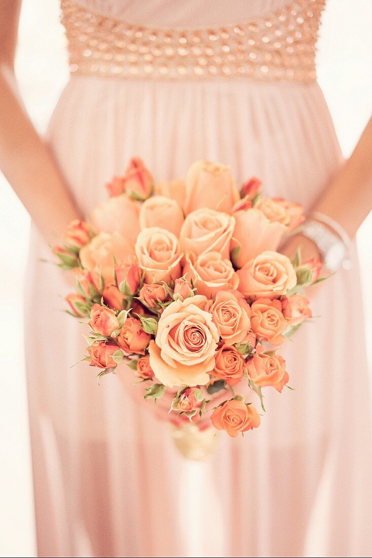Romantic bouquet of roses held in hands in front of wedding dress