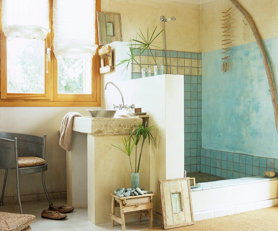 Bad mit mediterranem Flair, gemauerter Waschtisch an halbhoher Trennwand vor Duschbereich, gefliest und teilweise blau getönt