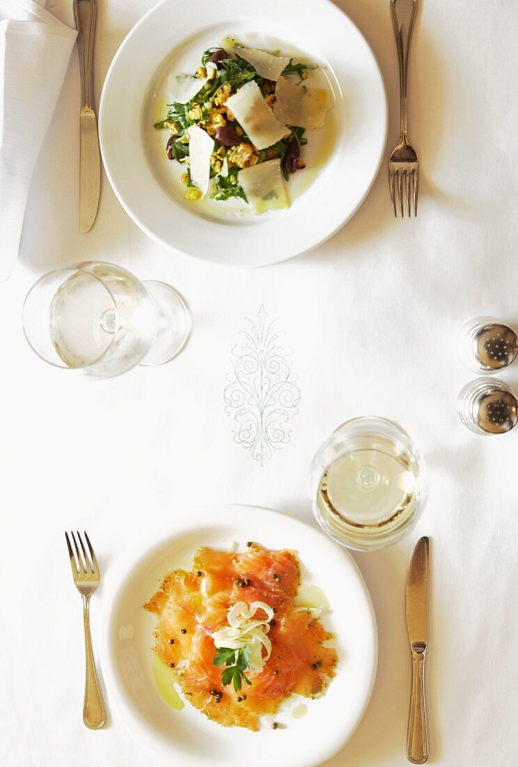 A festively laid table, seen from above, laid with rocket salad and salmon carpaccio