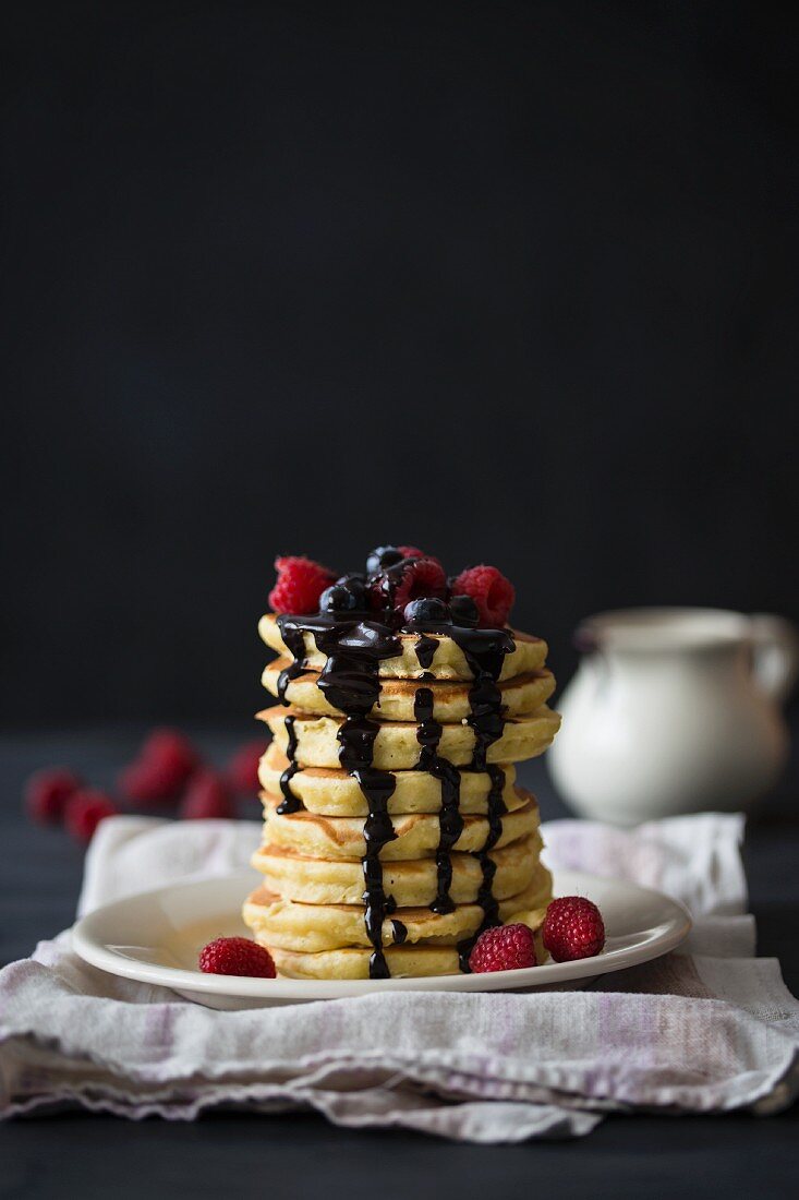 A stack of pancakes with berries and chocolate sauce