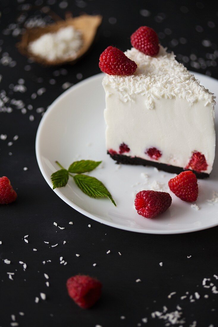 A slice of coconut cheesecake with fresh raspberries