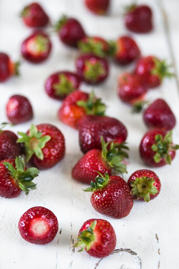 Frische Erdbeeren, verstreut auf weißem Holzuntergrund