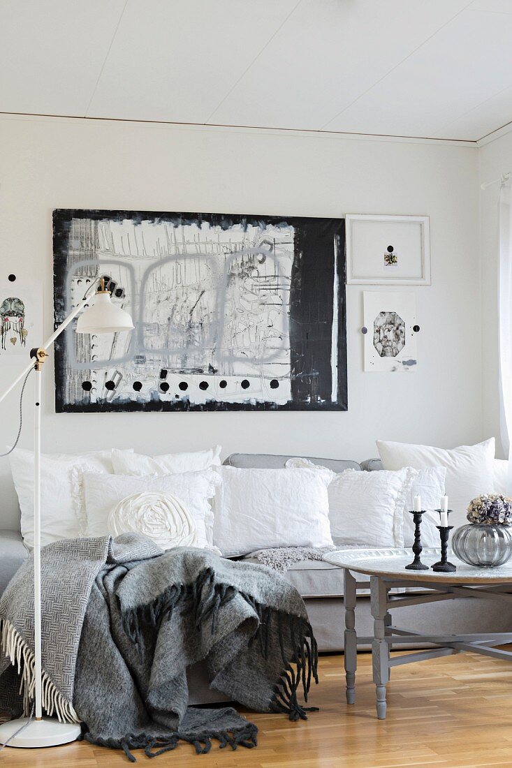 White, vintage-style cushions on grey sofa below black and white artwork