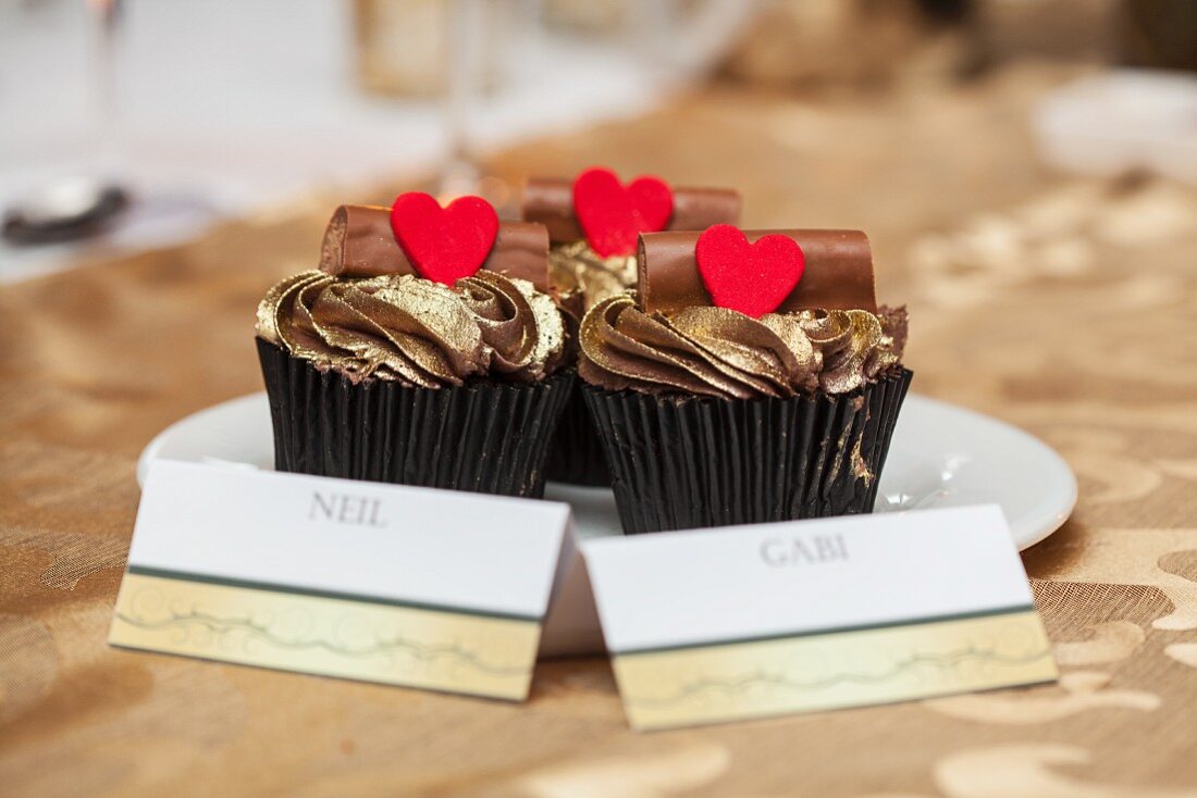 Cupcakes mit Goldglasur, Schokobaumstämmen und Herzen bei einer Hochzeit