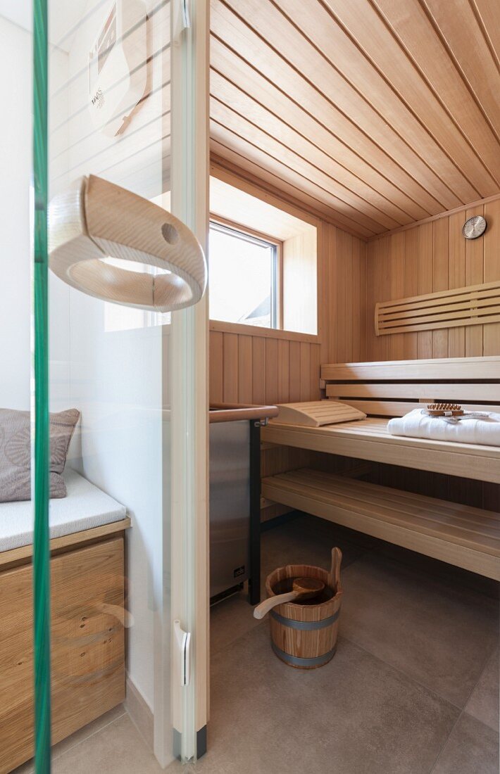 A view into an elegant sauna with a window and sauna utensils