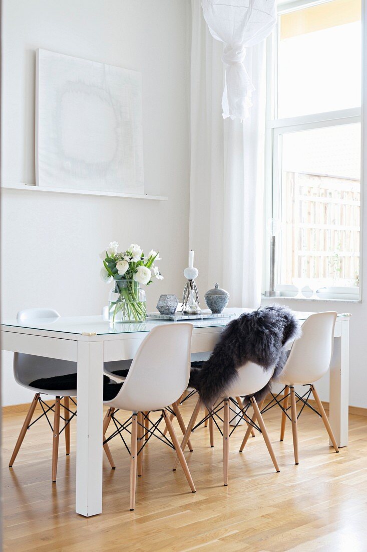 White shell chairs and table with glass top in modern dining room