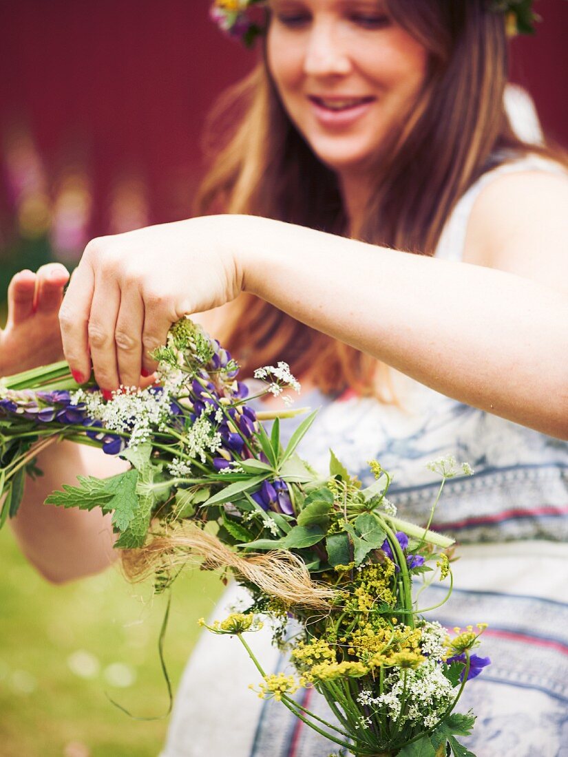 Woman tying wreath of flowers for midsummer festival