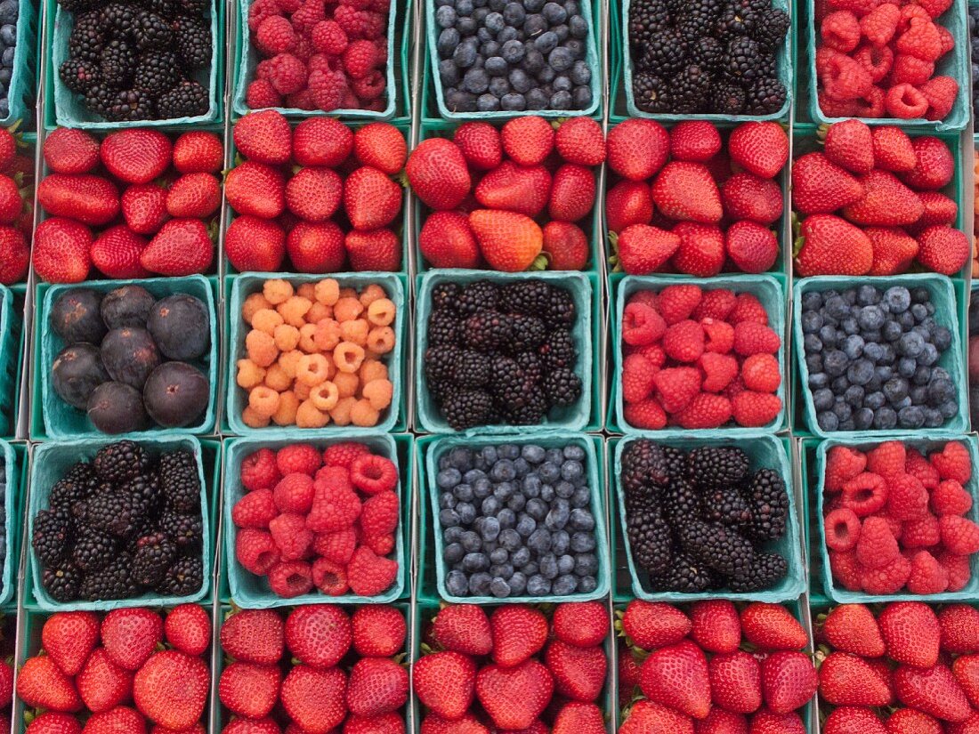 Viele verschiedene Beeren und Feigen in Pappschalen auf Markt