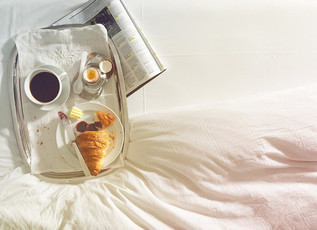 Breakfast in bed with coffee, egg and croissant