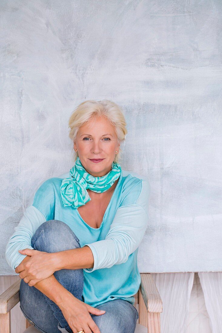 An older woman wearing a turquoise top, a scarf and jeans