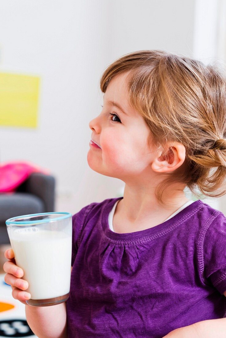 A little girl holding a glass of milk