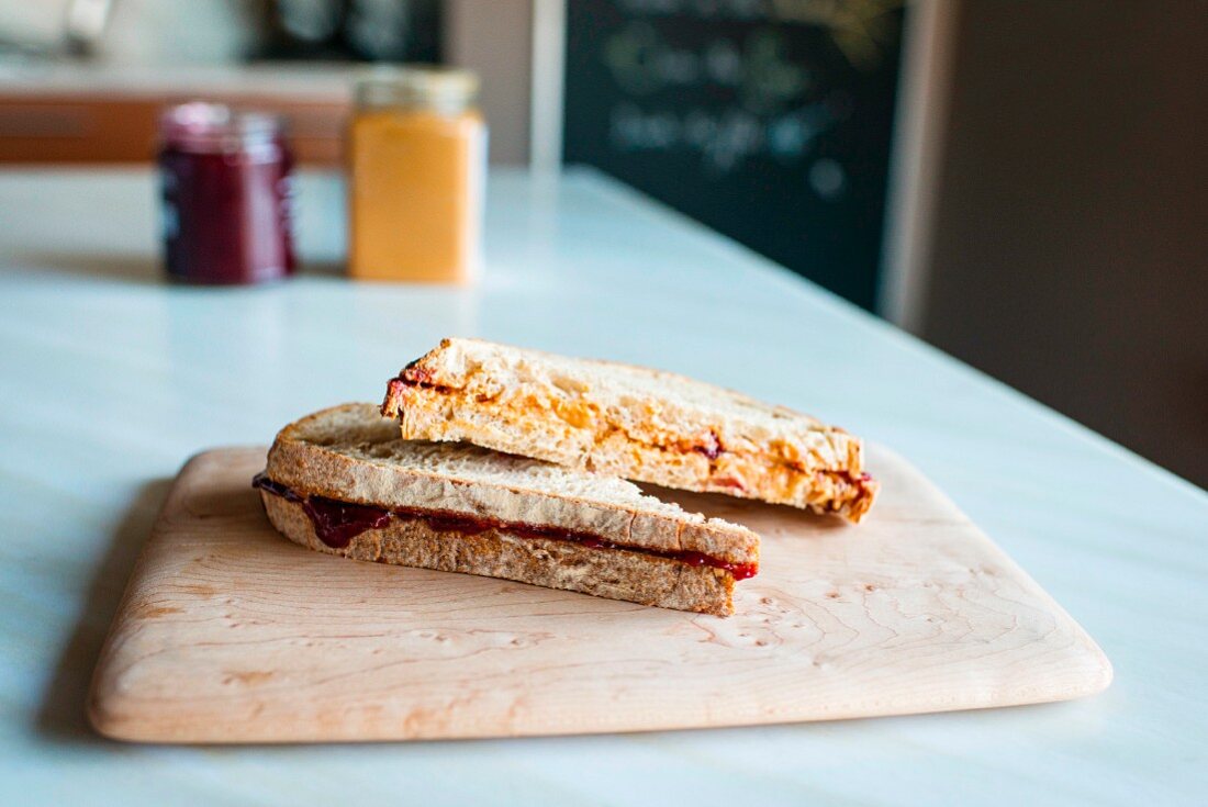 Two toasted sandwiches on a wooden board on a kitchen table