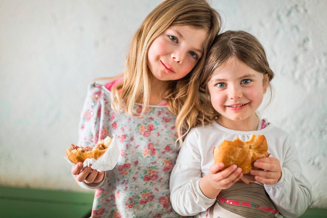 Two little girls eating sandwiches
