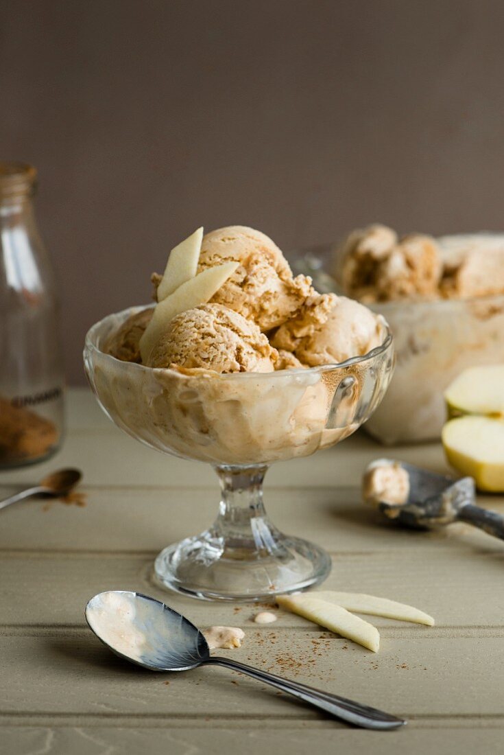 Apple, toffee and cinnamon ice cream in a glass bowl with apple wedges