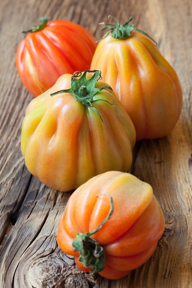 Four beefsteak tomatoes from Sicily on a wooden surface