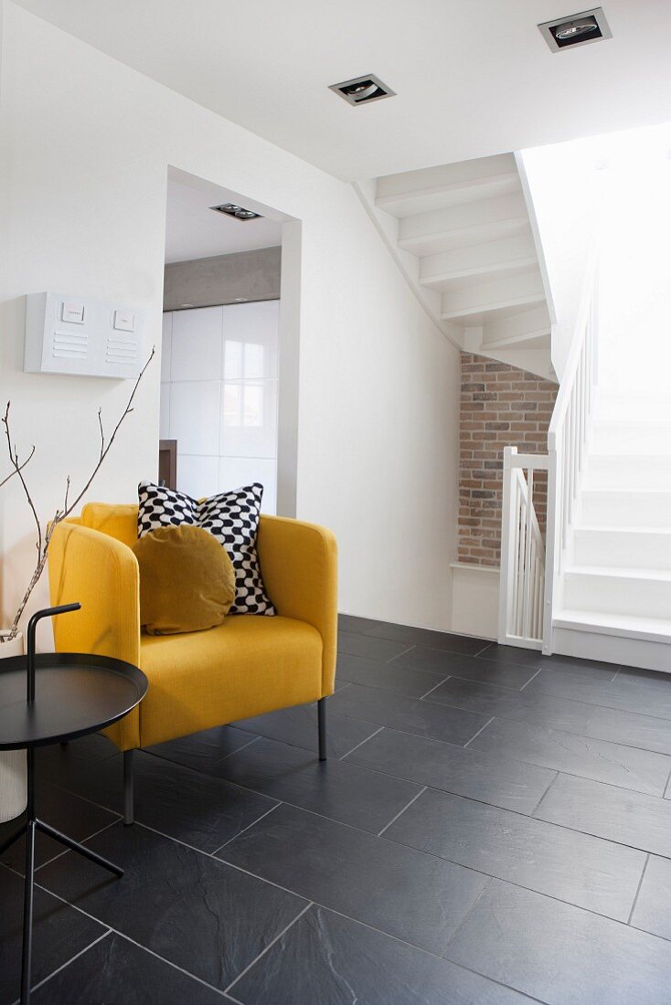 Yellow armchair providing a splash of colour in black and white hall