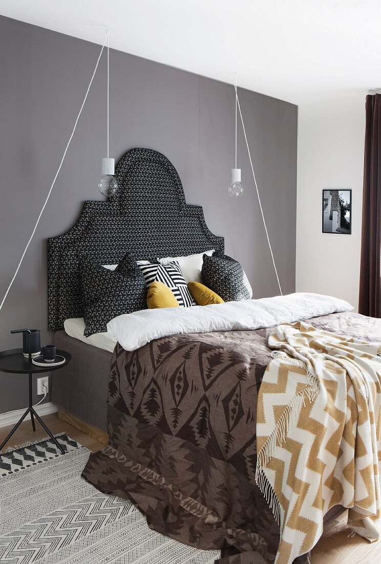 Textiles with various patterns on bed with upholstered headboard
