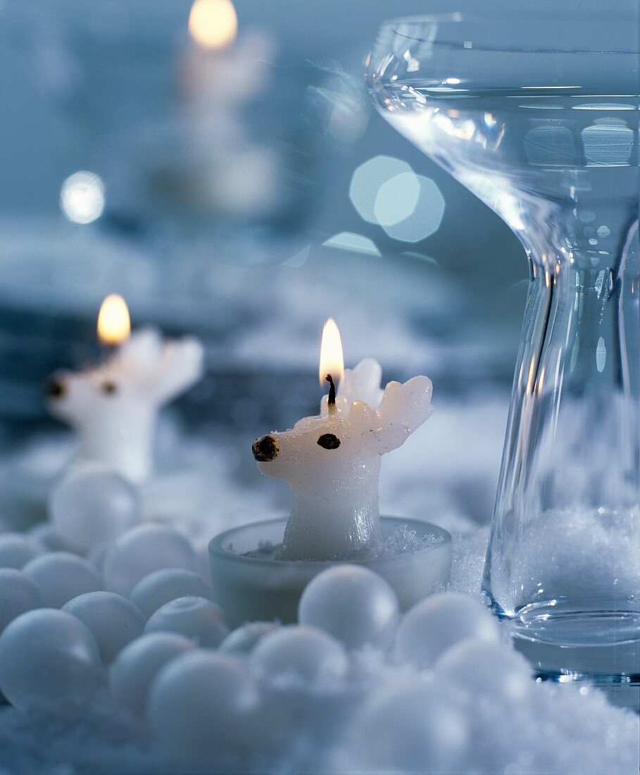 Reindeer-shaped tealights surrounded by white baubles & glass vase