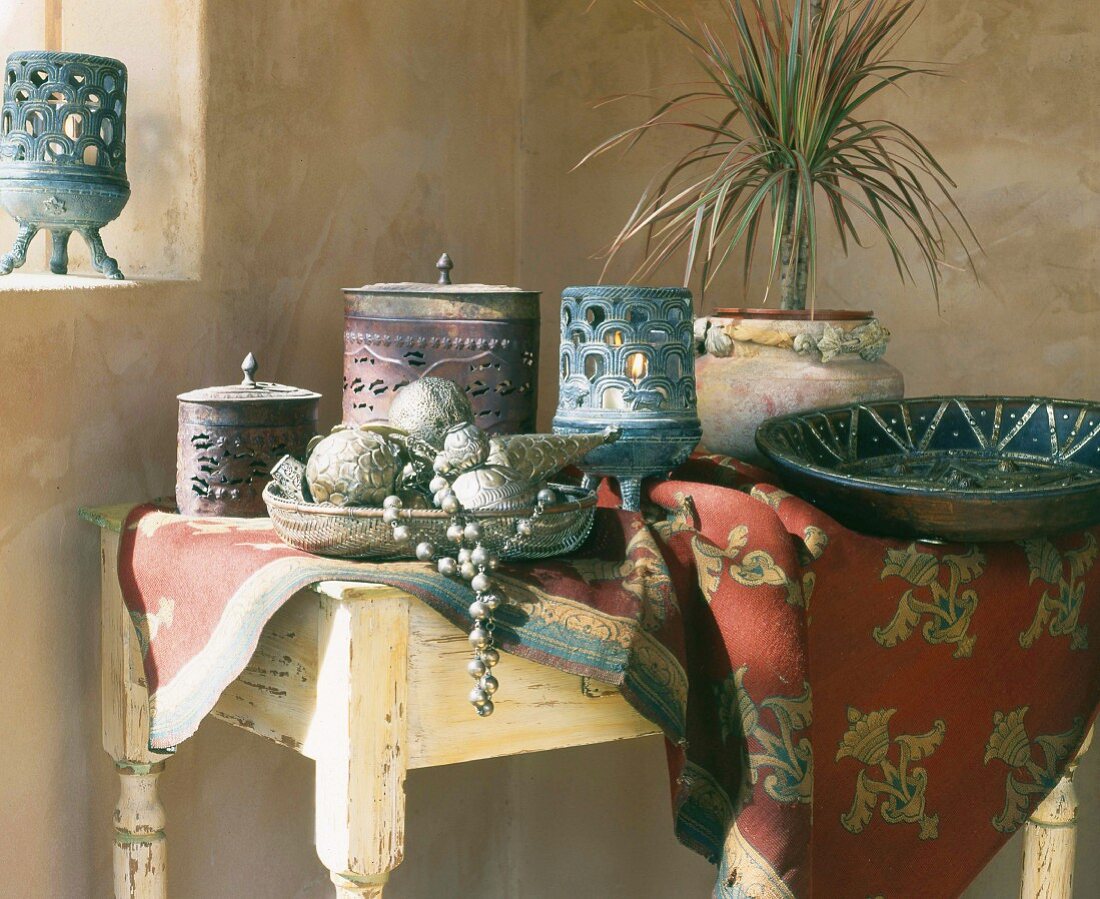 Oriental-style bowls and lidded jars on tablecloth on rustic table in corner
