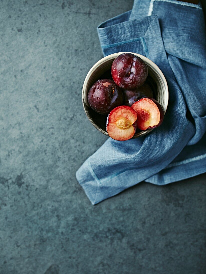 Red organic plums in a bowl