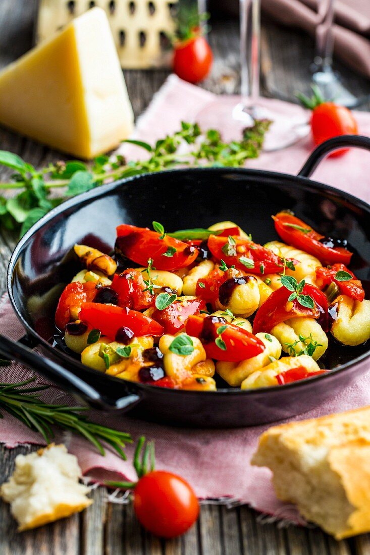Gnocchi with tomatoes, olives and fresh herbs in a pan