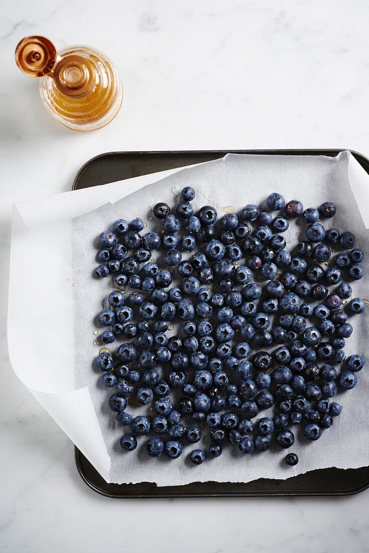 Frische Blaubeeren beträufelt mit Honig auf Backpapier & Backblech