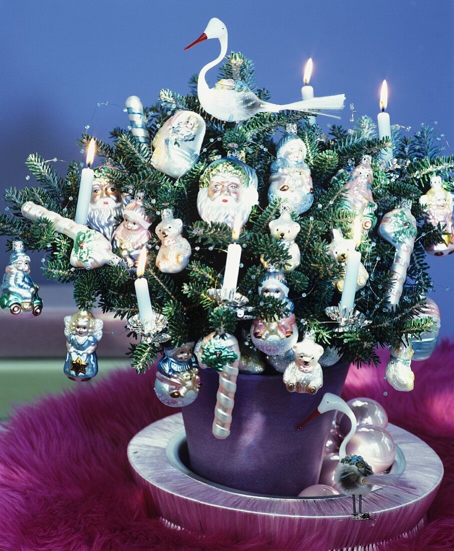 Tiny Christmas tree lavishly decorated with lit candles & baubles