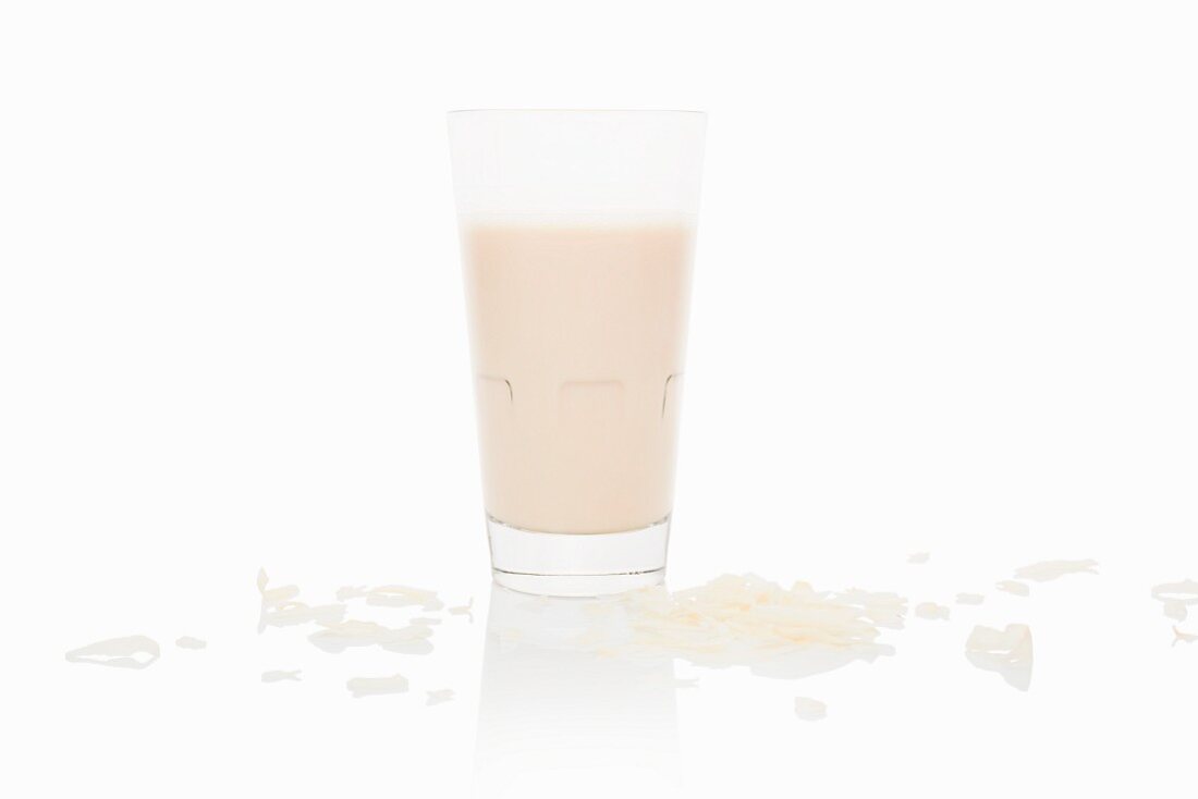 A glass of coconut milk on a white surface