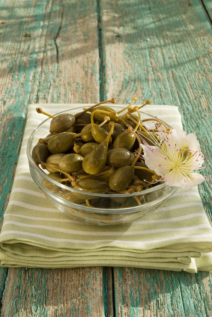 Caper fruits in a glass bowl on a wooden table