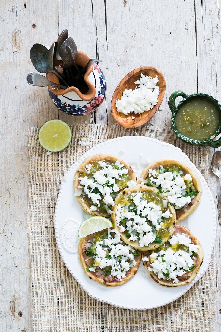 Spicy corn tartlets with a green sauce and cheese